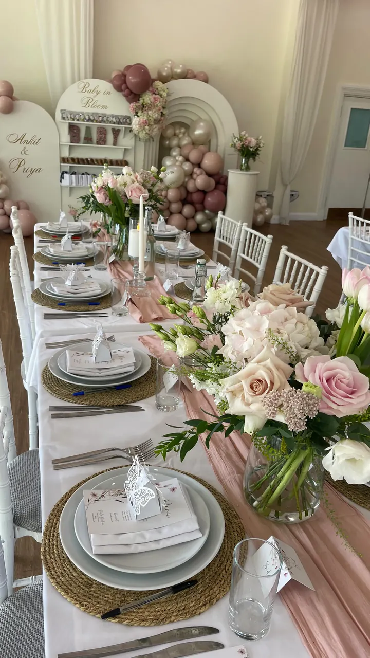 Long table laid with pink florals, pampas and gold-rimmed plates for a Baby in Bloom baby shower