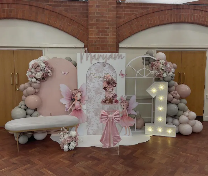 Pink and blush arch backdrop with a fairy cut-out, pink florals and a light-up 1 for a first birthday