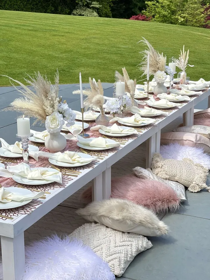 Outdoor low table styled with pampas grass, candles and cushions for a garden celebration