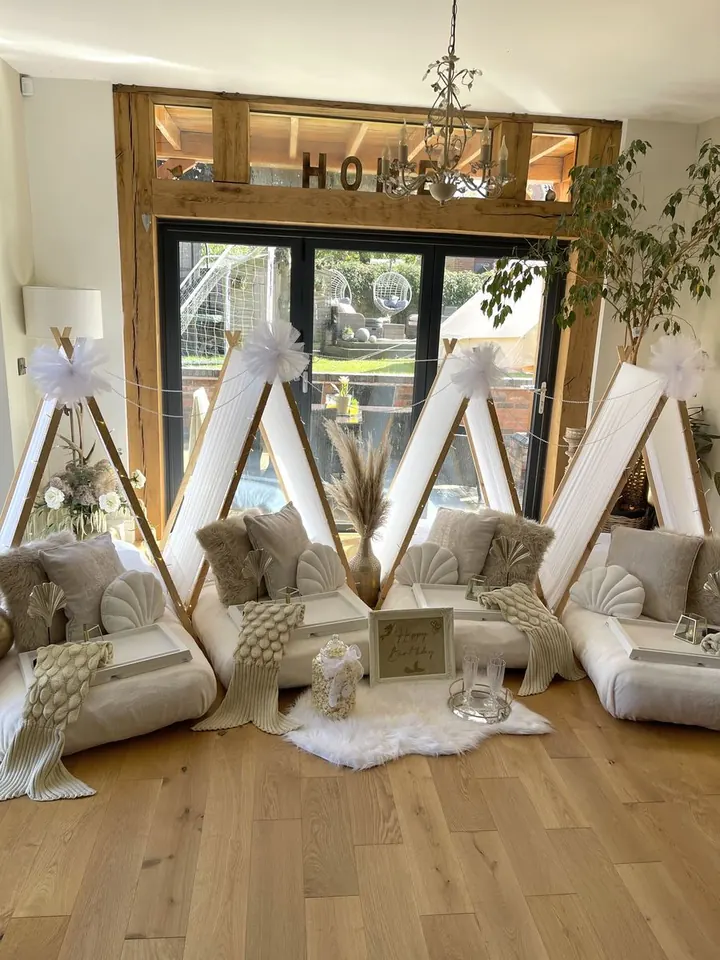 Indoor sleepover party with three teepees, cushions, pampas and fairy lights