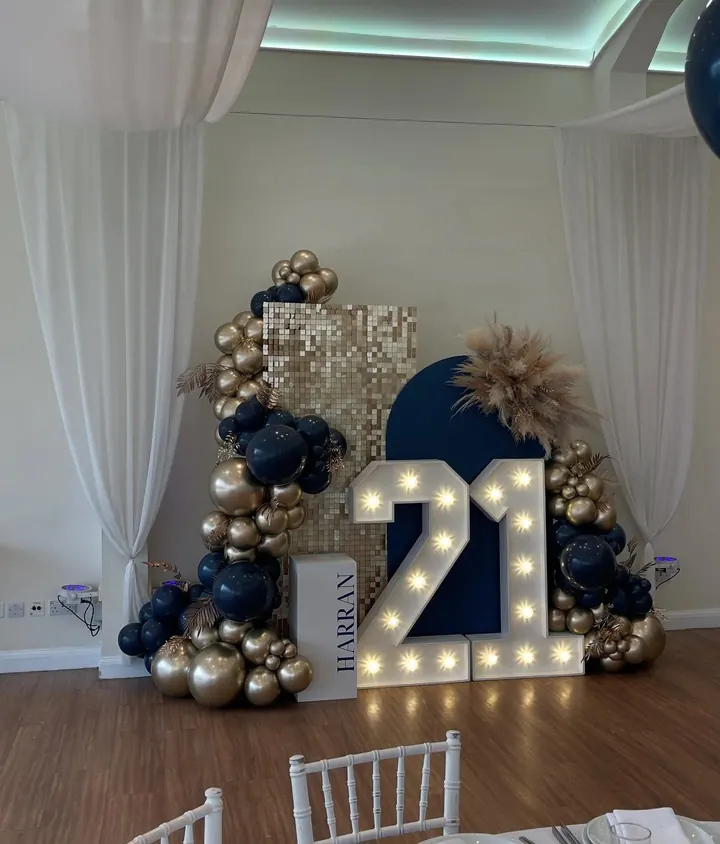 Light-up 21 numbers with a navy and gold balloon garland, a gold sequin panel and pampas