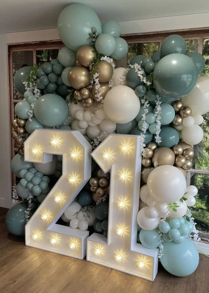 Sage green, gold and cream balloon garland around light-up 21 numbers